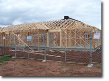 Photo of a timber house frame with a temporary fence around it.