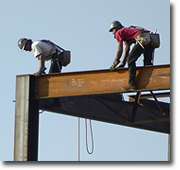 Photo of two men working on a large steel frame.