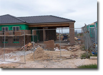 Photo of a site with a building under construction. The site has a fence around it. 