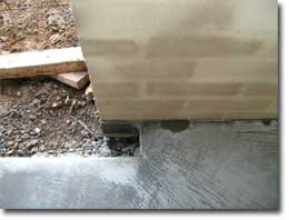 Photo of a concrete slab joining with a brick wall. 