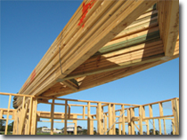 Photo of a stack of roof trusses resting on top of the frame of a house.